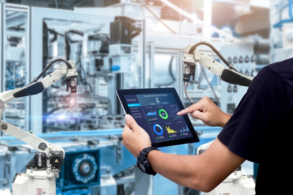 Hands holding tablet on blurred automation machine as background
