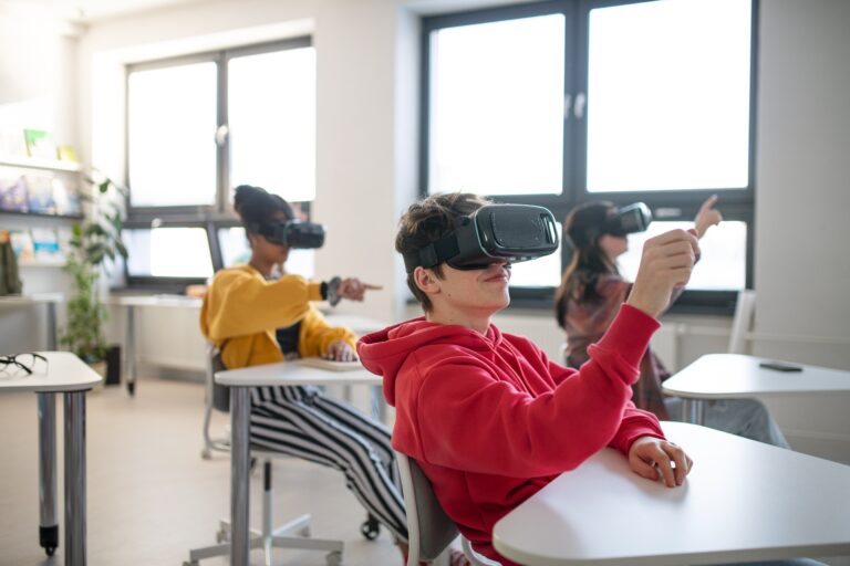 Teenage students wearing virtual reality goggles at school in computer science class.