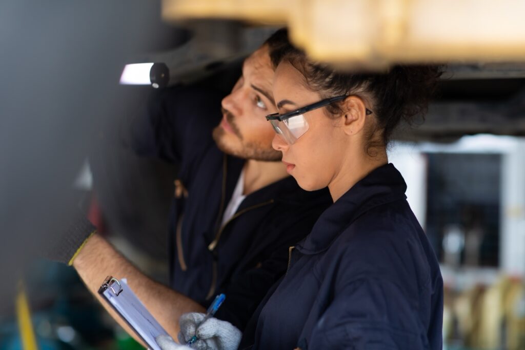 Female trainee Mechanics Working Underneath Car Together Car maintenance and auto service garage. Car maintenance and auto service