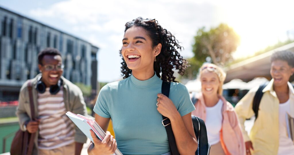 Walking, happy and girl with friends at university for learning, bonding and talking with fun. People, school and group of gen z students commuting outdoor ready for education at college campus.