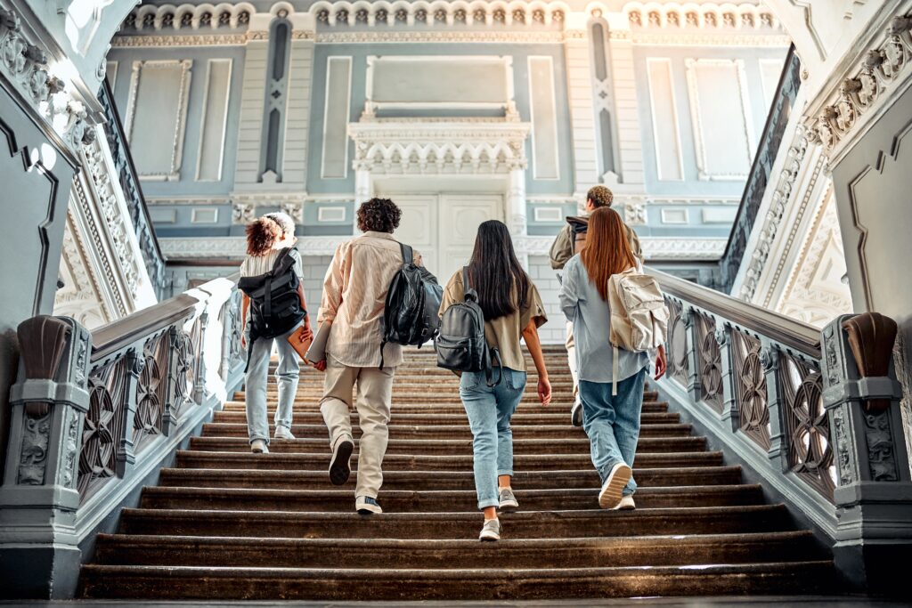 A group of college students walking up the stairs with backpacks on their shoulders. Motivation and academic success