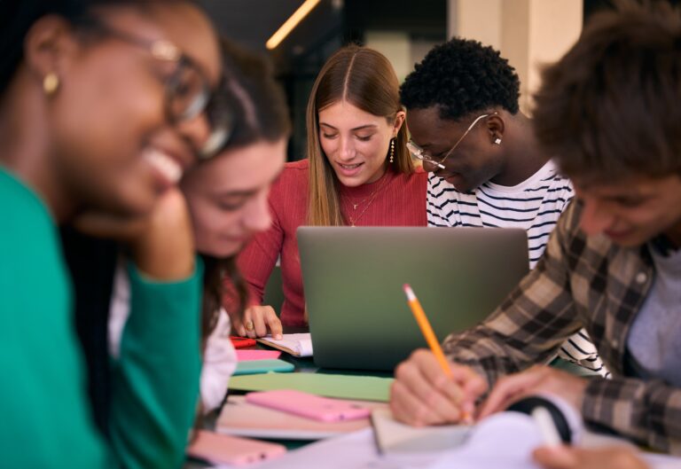 Selective focus on multiracial couple of concentrated students doing homework together using notebook sitting in study room. Group of academic diverse people working together on university campus
